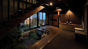 A dimly lit interior with a wooden staircase, a small garden area, and a traditional Japanese sliding door. - WATAYA (Hakusan)