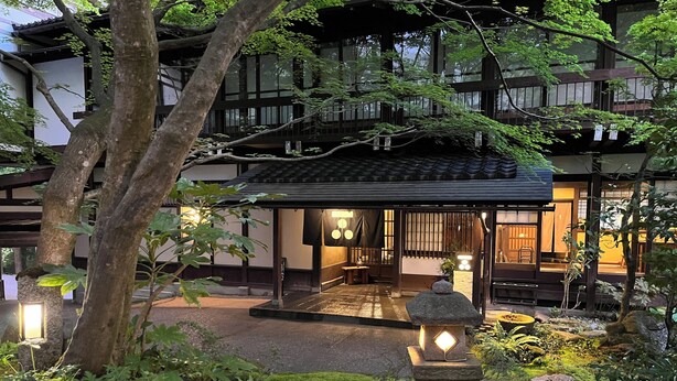 A traditional Japanese-style building with a covered entrance, stone lanterns, and a well-maintained garden with moss and ferns. - WATAYA (Hakusan)