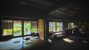 A traditional Japanese room with tatami flooring, sliding doors, and large windows overlooking a garden. - WATAYA (Hakusan)