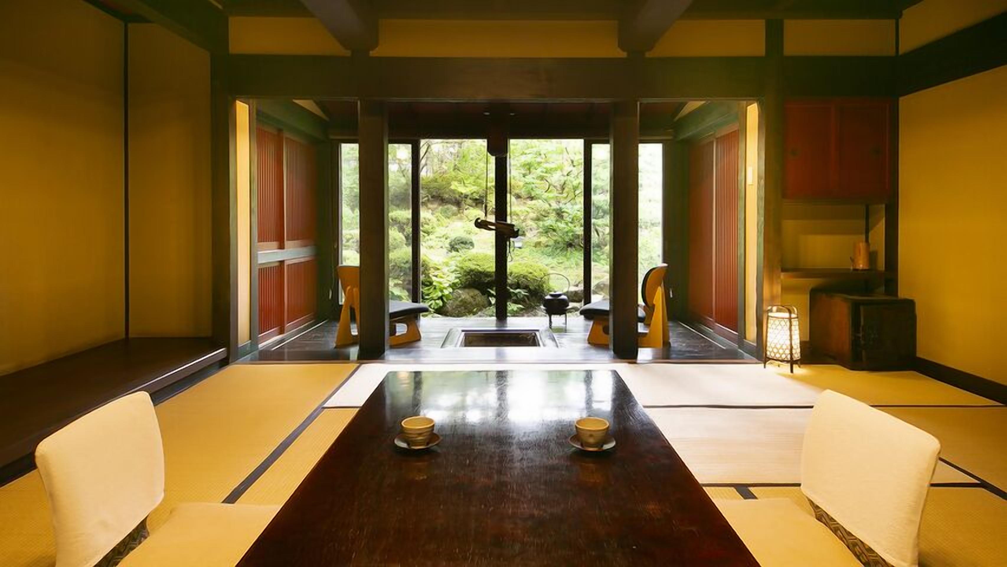 A traditional Japanese-style room with tatami flooring, a low table, and sliding doors leading to a garden.