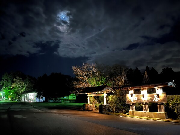 A nighttime view of a building with a signboard, a covered area, and a street. - WATAYA (Hakusan)