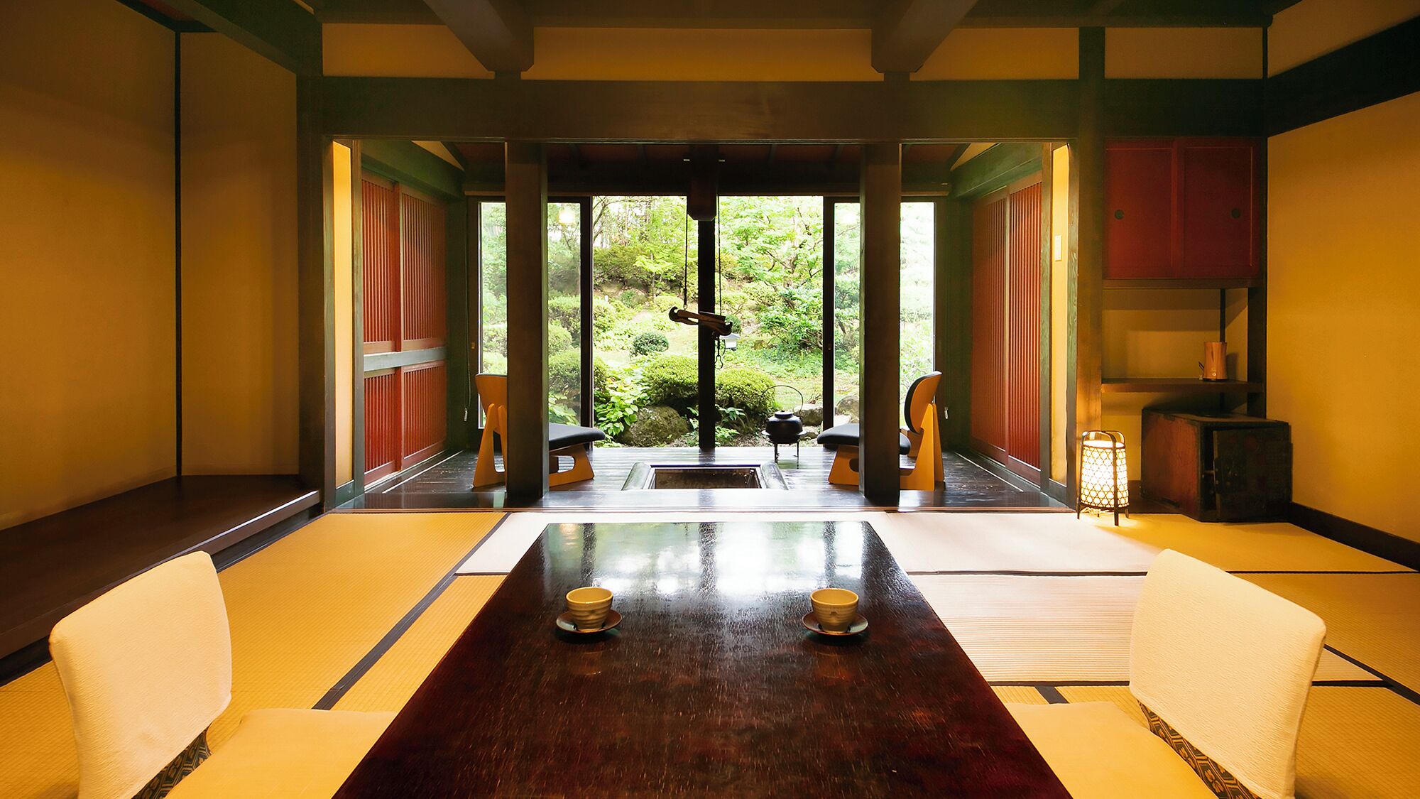 A traditional Japanese-style room with tatami flooring, a low table with two bowls, and sliding doors leading to a garden.