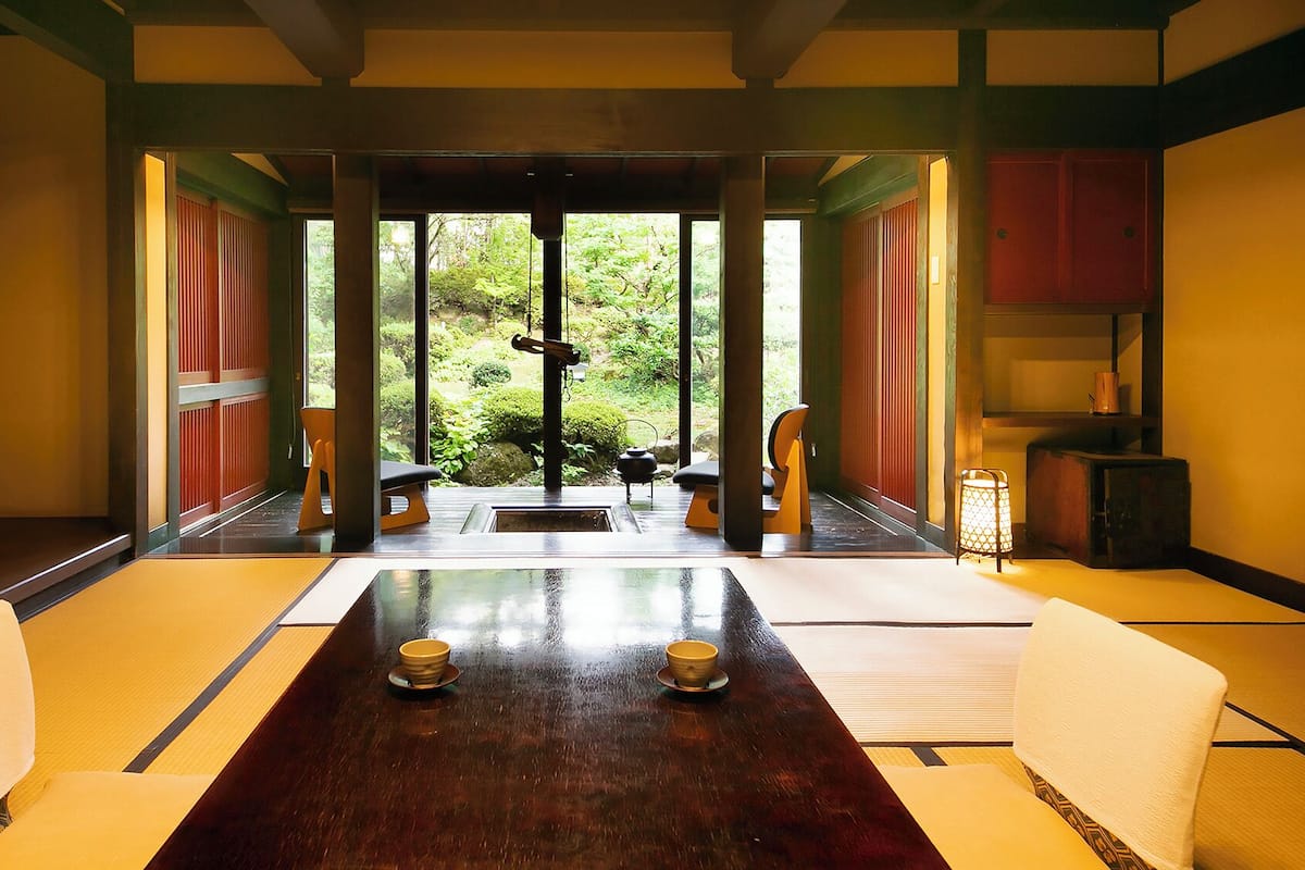 A traditional Japanese-style room with tatami flooring, a low table with two bowls, and sliding doors leading to a garden.