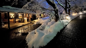 A snow-covered outdoor area with a building that has a traditional architectural style, featuring a wooden structure and a tiled roof. - WATAYA (Hakusan)