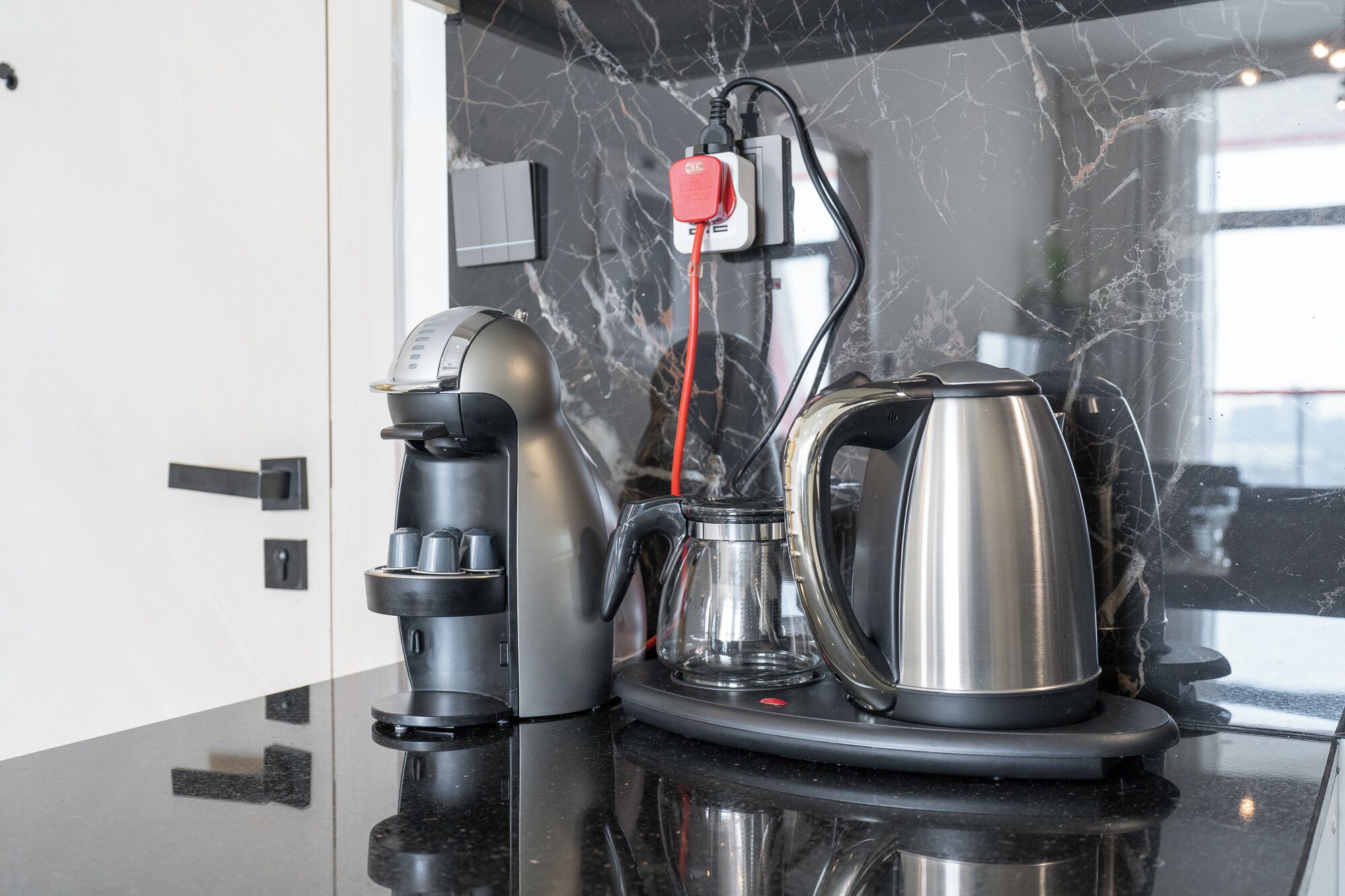 A kitchen counter with a coffee machine, a kettle, and a power strip.