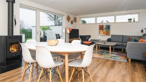 A modern living room with a fireplace, dining area, and seating. - 5 Star Holiday Home in Borkop (Borkop)