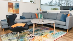 A modern living room with a grey sofa, black armchair, and a colorful rug. - 5 Star Holiday Home in Borkop (Borkop)