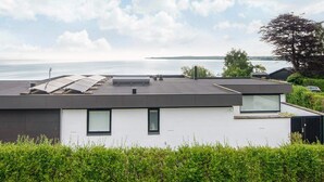 A modern building with a flat roof, large windows, and a view of a body of water. - 5 Star Holiday Home in Borkop (Borkop)