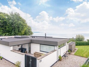 Una casa moderna con techo plano, ventanas amplias y vista al mar.