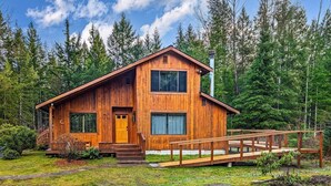 Une cabane en bois dotée d’un porche à l’avant, d’un escalier menant à l’entrée et d’une terrasse en bois.