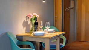 A dining table with a bottle of wine, two glasses, and a vase of flowers. - Apartment with shared wellness and fitness (Piesendorf)