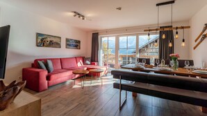 Ein modernes Wohnzimmer mit einem roten Sofa, Holzböden und einem Essbereich mit Tisch für zwei Personen.