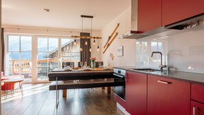 Eine moderne Küche mit roten Schränken, einem eingebauten Ofen und einem großen Fenster mit Blick auf eine Terrasse.