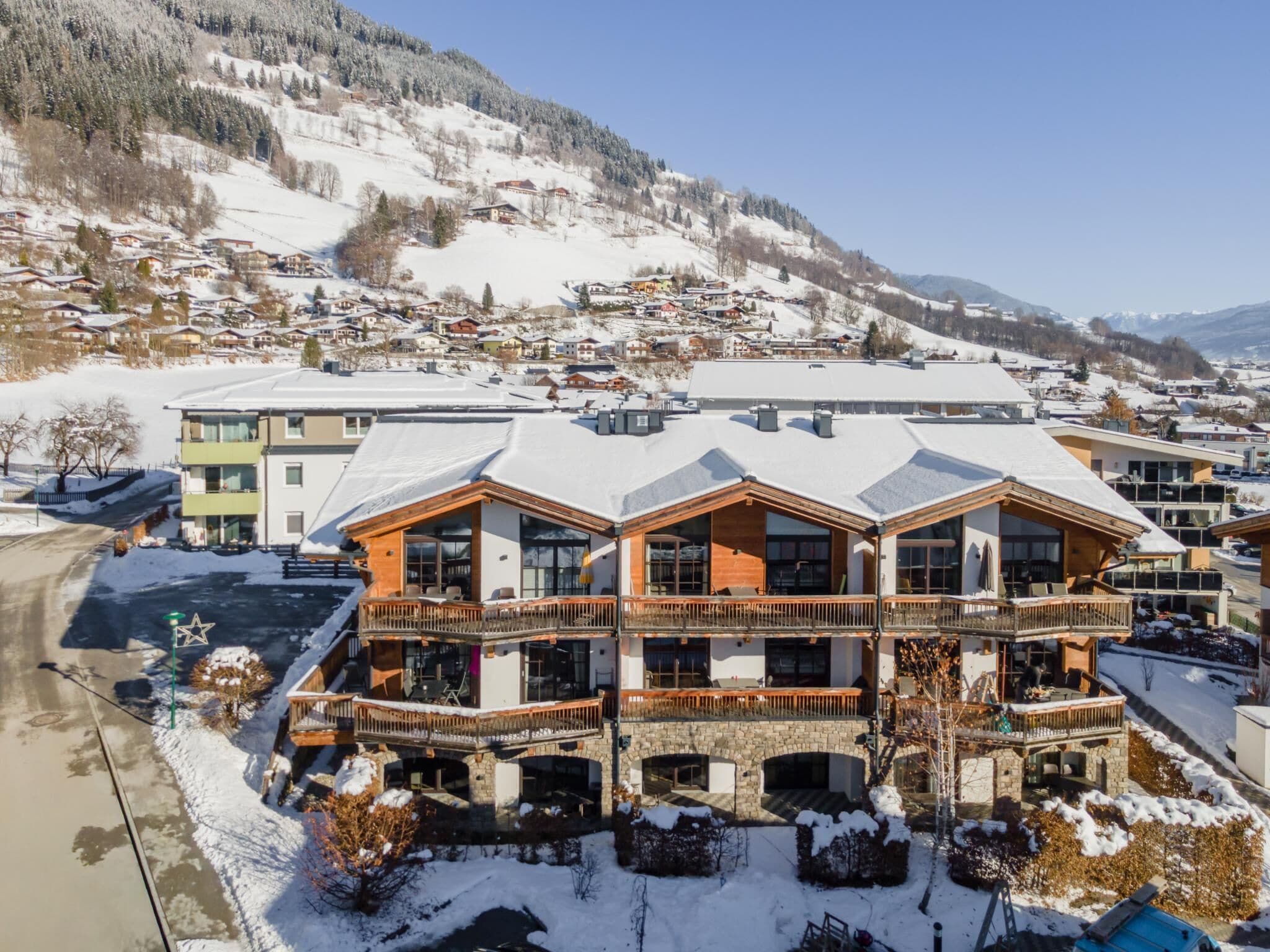 Un hôtel à plusieurs étages offrant une vue sur une station de ski, doté de balcons et d’une façade en pierre.