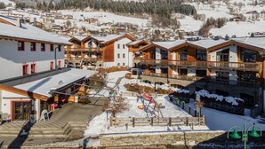A ski resort with wooden buildings, a ski lift, and snow-covered mountains. - Cosy apartment with a large balcony and wellness (Piesendorf)