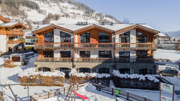 A multi-story chalet with balconies, set in a snowy mountainous area. - Cosy apartment with a large balcony and wellness (Piesendorf)
