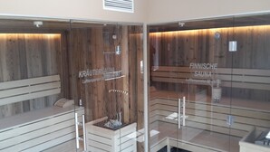 A sauna with wooden walls and benches, labeled 'KRÄUTERSAUNA' and 'FINNISCHE SAUNA'. - Cosy apartment with a large balcony and wellness (Piesendorf)
