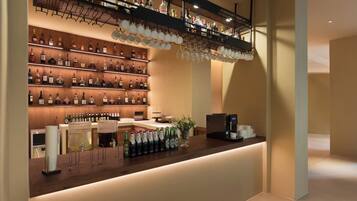 A bar area with shelves of liquor bottles, a coffee machine, and a counter with glasses and bottles.