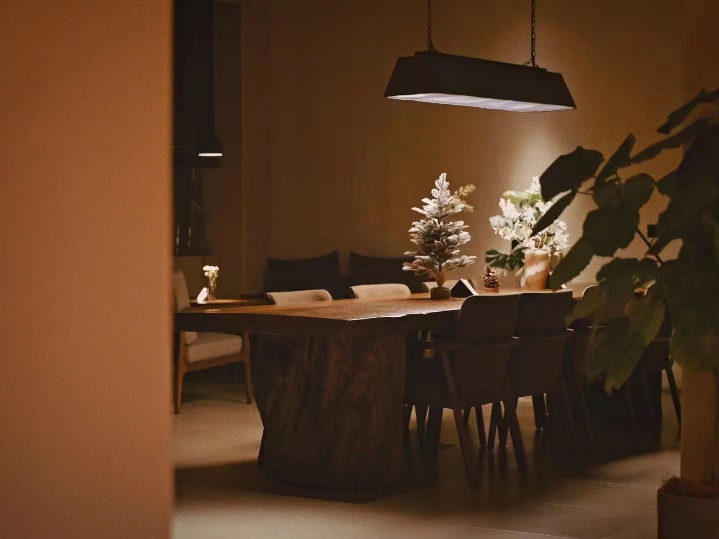 Un espace repas comprenant une table en bois, des chaises et un luminaire suspendu.