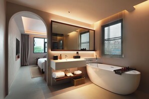 Un baño moderno con una bañera independiente, un espejo grande y un tocador con lavabo y encimera.
