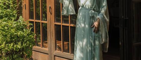 Uma pessoa vestida com traje típico em frente a uma estrutura de madeira com janelas em estilo de grade.