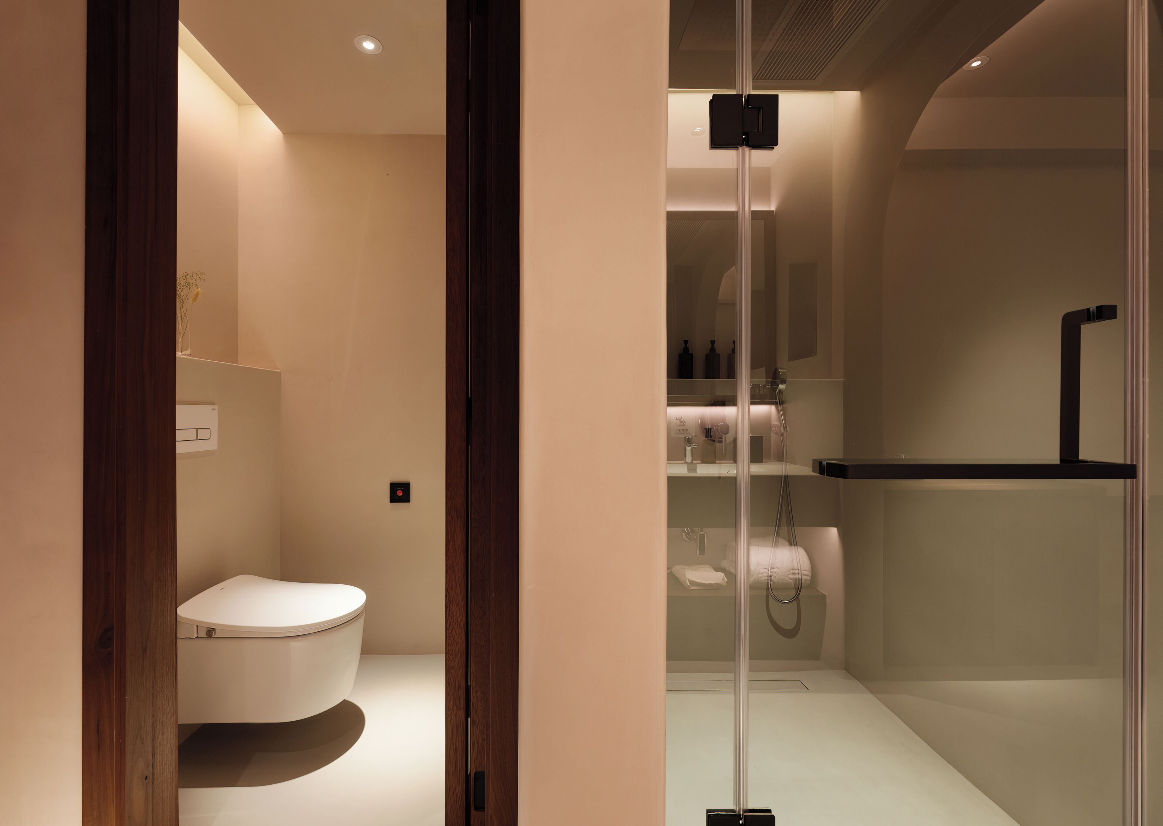 Une salle de bain moderne comprenant des toilettes, un espace douche et une paroi de séparation en verre.