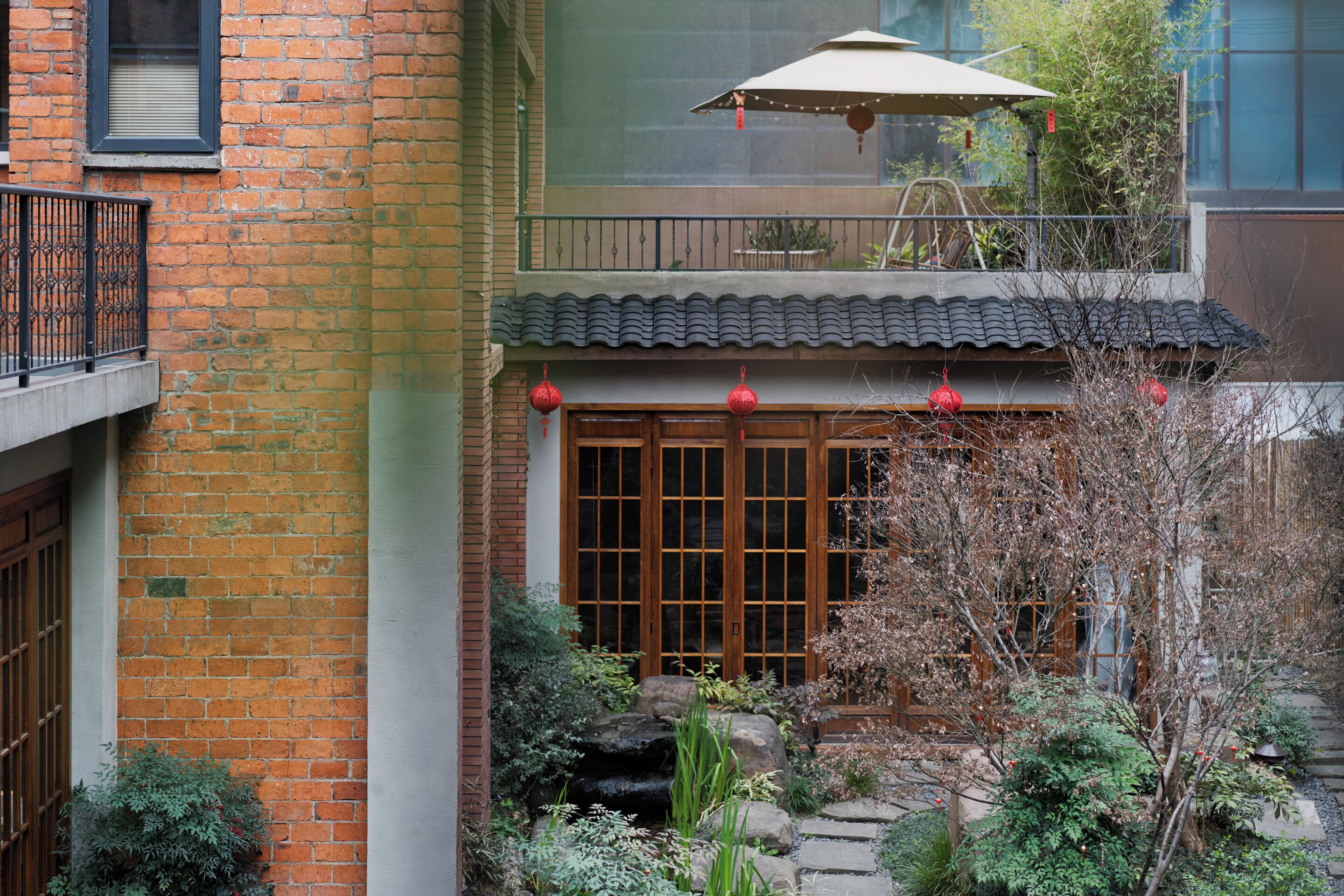 A traditional courtyard with a tiled roof, wooden doors, and a small rock garden.
