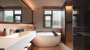 A modern bathroom with a large bathtub, a white vanity, and a large mirror.
