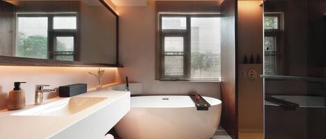 A modern bathroom with a large bathtub, a white vanity, and a large mirror.