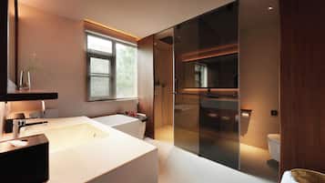 Un baño moderno con una bañera grande, una zona de ducha separada y un inodoro con cerramiento de vidrio.
