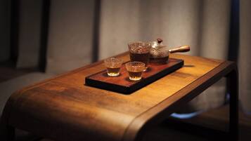 A wooden table with a tray holding a teapot and two cups.