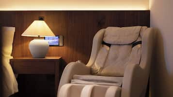 Un fauteuil de massage doté d’un panneau de commande, une table de chevet avec une lampe et un mur en bois.