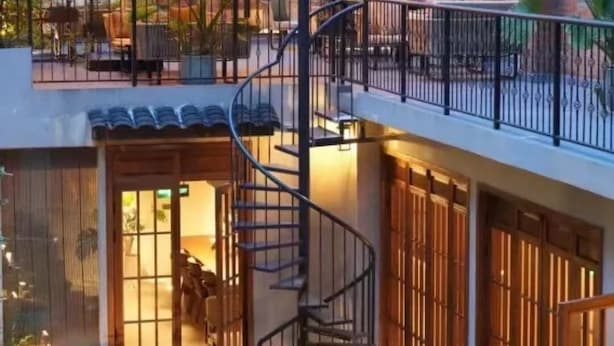 Un edificio de varios niveles con una escalera en espiral, espacio para sentarse al aire libre y un pequeño jardín.