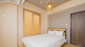 Une chambre à coucher avec un lit, des stores en bois, une armoire en bois et un luminaire fixé au plafond.