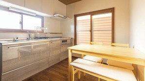 Une cuisine moderne avec des meubles en bois, un plan de travail en acier inoxydable et un coin repas comprenant une table et un banc en bois.