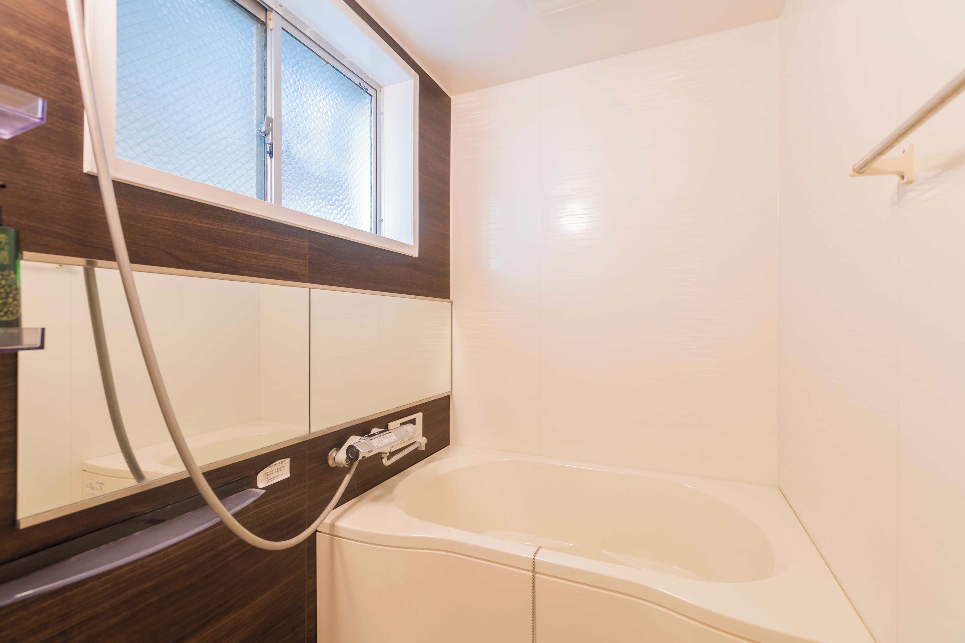 Ein Badezimmer mit Badewanne, Fenster und Duschschlauch.