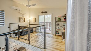 A spacious living area with a wooden floor, a sofa, a coffee table, and a bookshelf. - Hike & Explore: 60-Acre Outdoor Retreat in Tyler! (Tyler)