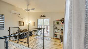 Un amplio salón con suelo de madera, un sofá, una mesa de centro y una estantería.