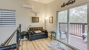 A cozy living room with a sofa, a small table, and a large window with a view of the outdoors. - Hike & Explore: 60-Acre Outdoor Retreat in Tyler! (Tyler)