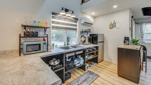 A modern kitchen with a built-in microwave, sink, and stove. There is a window above the sink and a small refrigerator to the right. - Hike & Explore: 60-Acre Outdoor Retreat in Tyler! (Tyler)