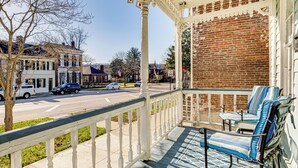 A porch with a brick wall, a white railing, and a blue and white striped chair.