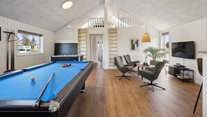 Ett rymligt rum med ett biljardbord, bekväma sittplatser, en TV och en balkong med utsikt.