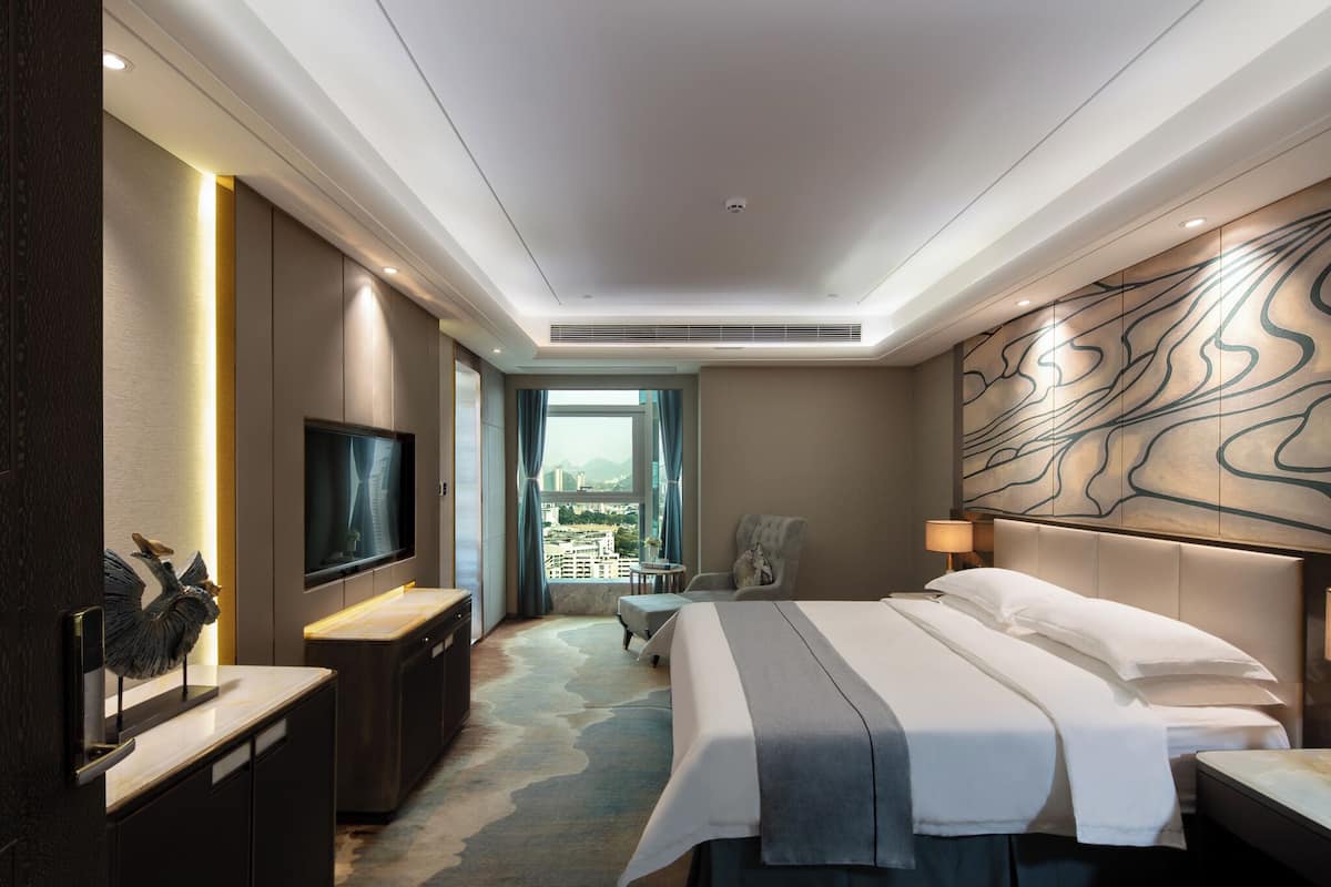 Una habitación de hotel moderna con una cama grande, un televisor de pantalla plana, un escritorio y vistas a la ciudad.
