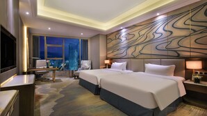 Quarto de hotel com cama grande, escrivaninha, cadeira, televisão e vista para a cidade.