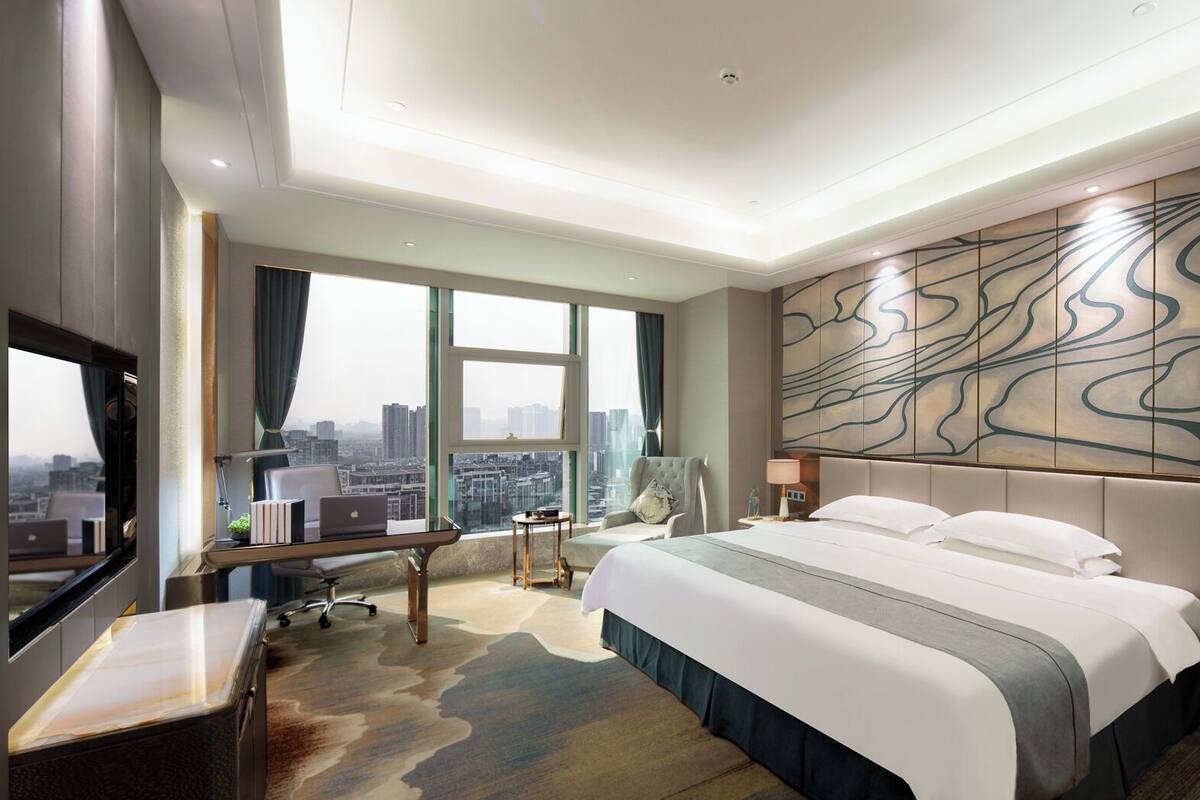 Una habitación de hotel moderna con una cama grande, un escritorio y vistas a la ciudad.