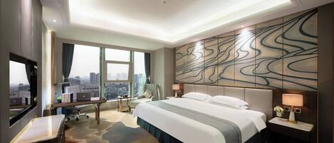 Quarto de hotel moderno com uma cama grande, uma mesa de escritório e vista para a cidade.