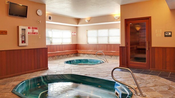 Ein Wellnessbereich mit zwei Whirlpools, einer Uhr und einem Schild mit der Aufschrift 'Tauchen verboten'.