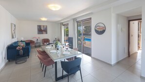 Una sala de estar moderna con una mesa de comedor de vidrio, un sofá azul y vistas al exterior.