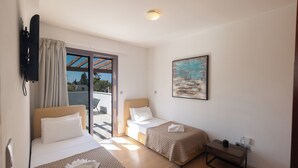 Habitación de hotel con dos camas, una mesita, un cuadro y un televisor.