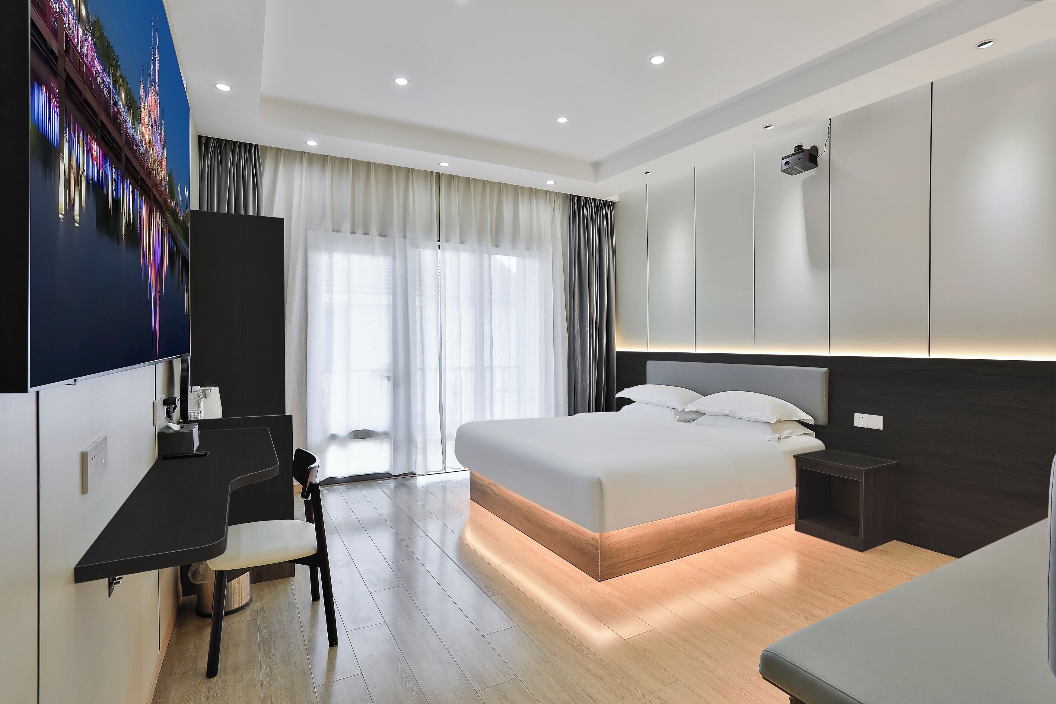 A modern hotel room with a large bed, a desk, and a chair.